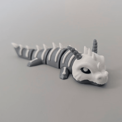 3D-printed Bone Dragon articulated flexi keychain in bone white, front view posed standing — 864 ToyLabs
Bone Dragon flexi keychain held in hand showing scale and skeletal detail — 864 ToyLabs