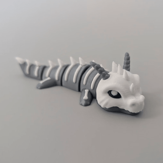 3D-printed Bone Dragon articulated flexi keychain in bone white, front view posed standing — 864 ToyLabs
Bone Dragon flexi keychain held in hand showing scale and skeletal detail — 864 ToyLabs