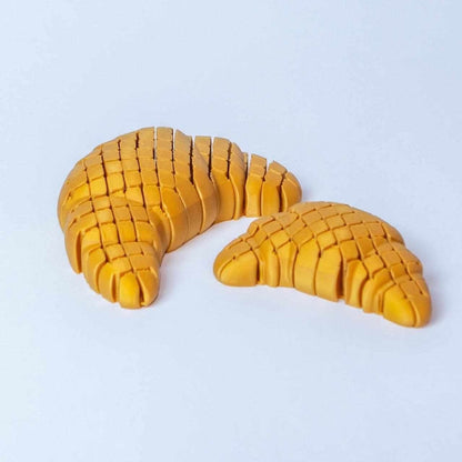 Articulated 3D printed Floppy Croissant fidget toy with flexible bending body
Floppy Croissant toy held to show its wiggly, poseable golden-brown segments
