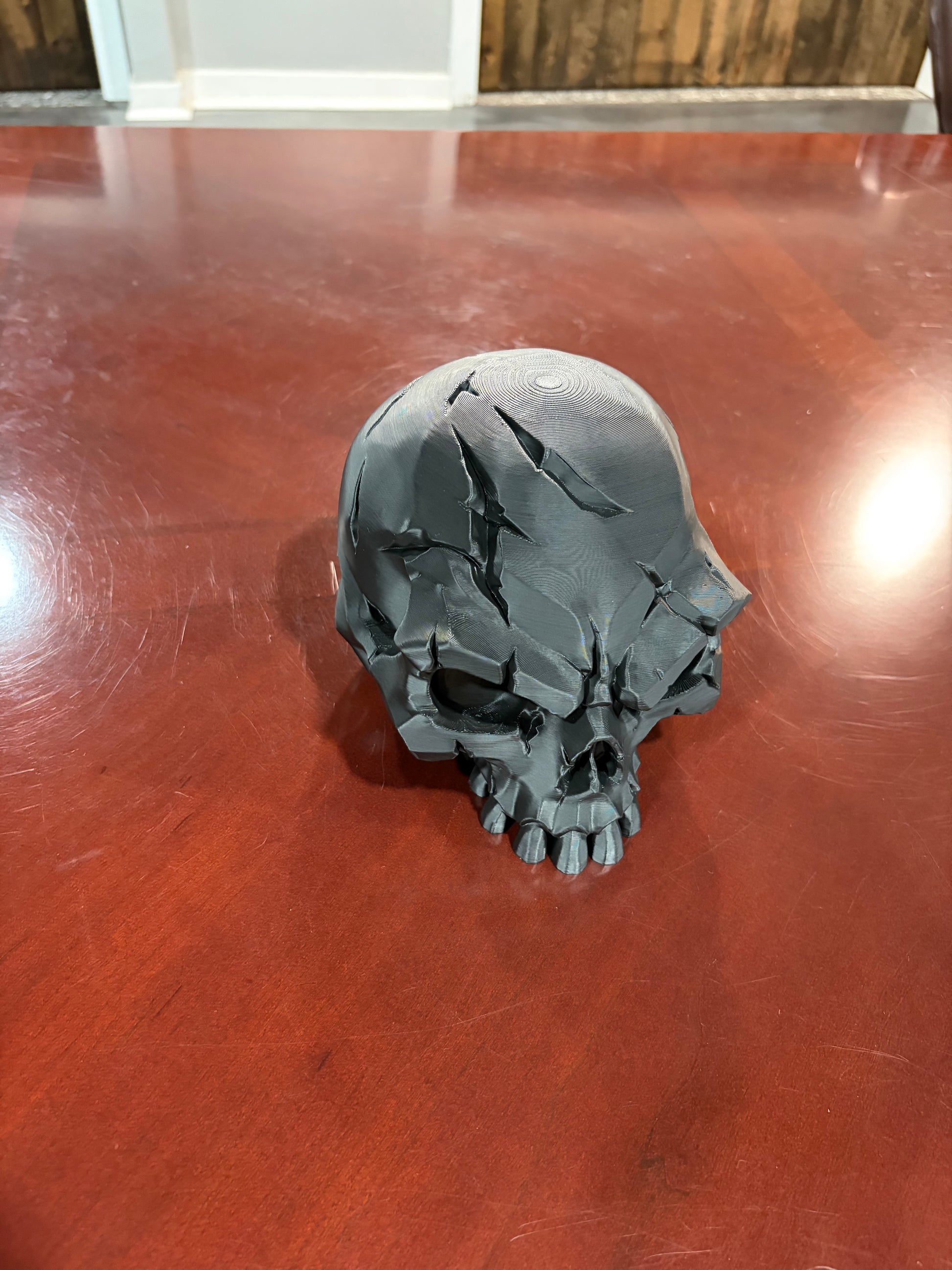 Black 3D printed battle scar skull display piece, top view
