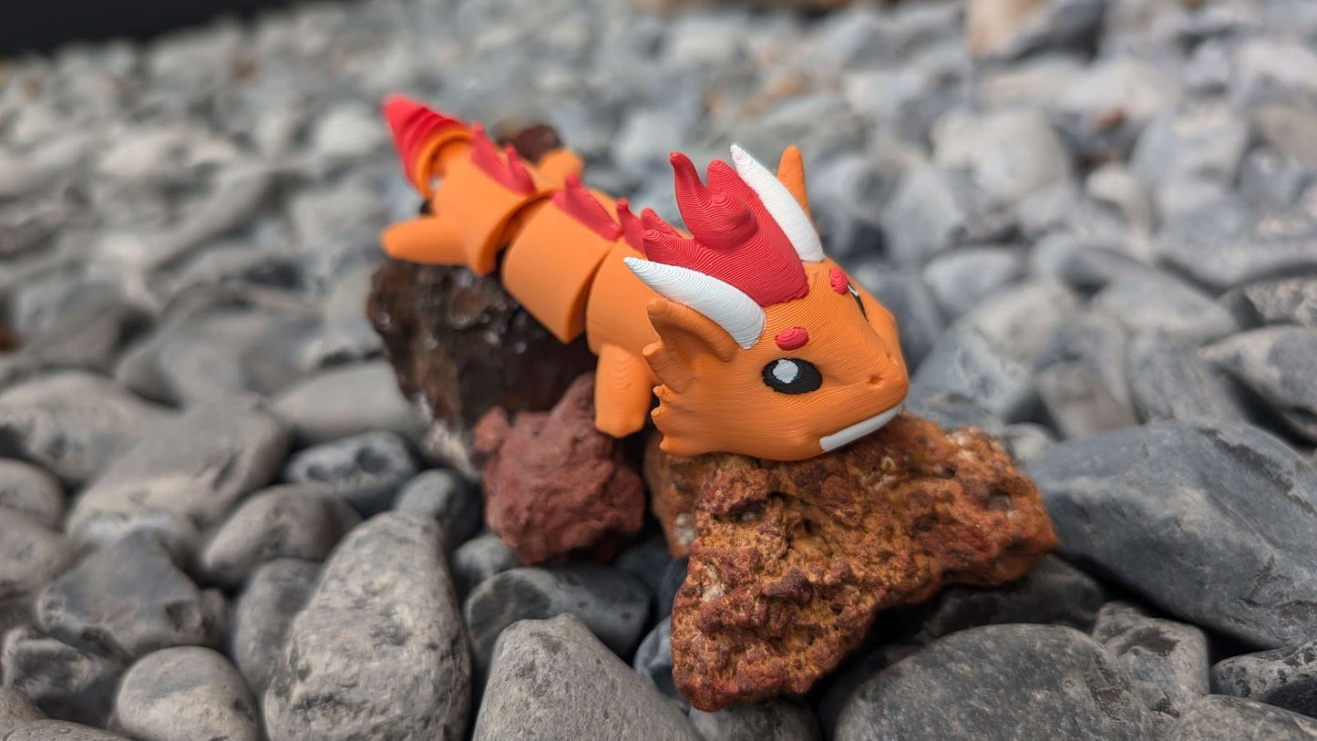 Fire Dragon articulated keychain posed on rocks, side view showing tail and wings — 864 ToyLabs