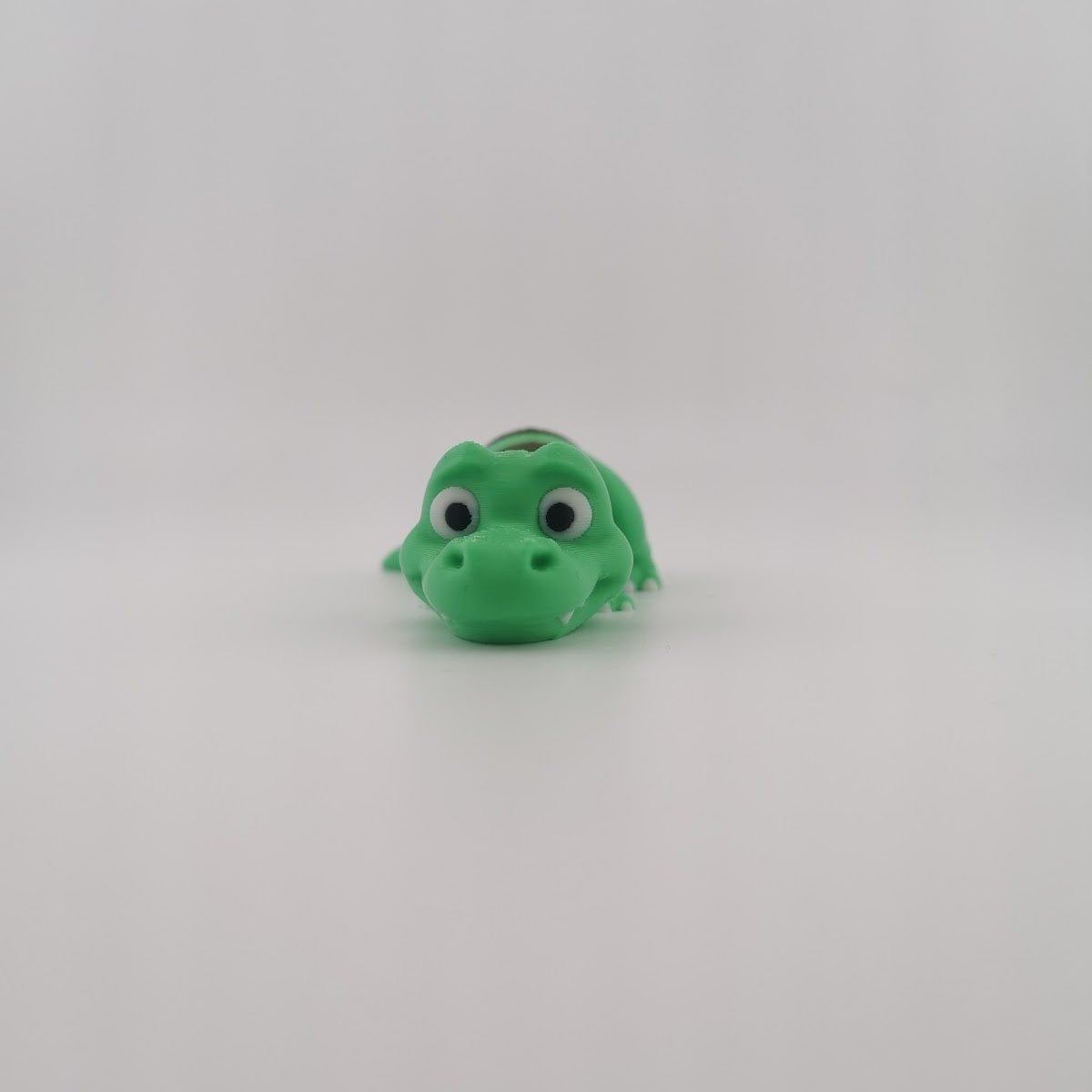 Green 3D printed articulated T-Rex dinosaur figure, side view
